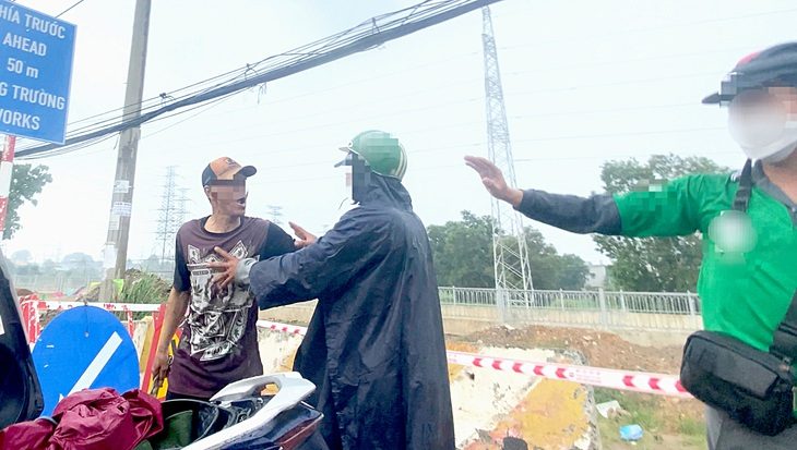 Ông Sáu (trái) cầm dây xích “dọa” một tài xế đón khách trên quốc lộ 13 (TP Thuận An, tỉnh Bình Dương). Thời điểm trên có một người đàn ông đứng ở giữa can ngăn - Ảnh: cắt từ clip